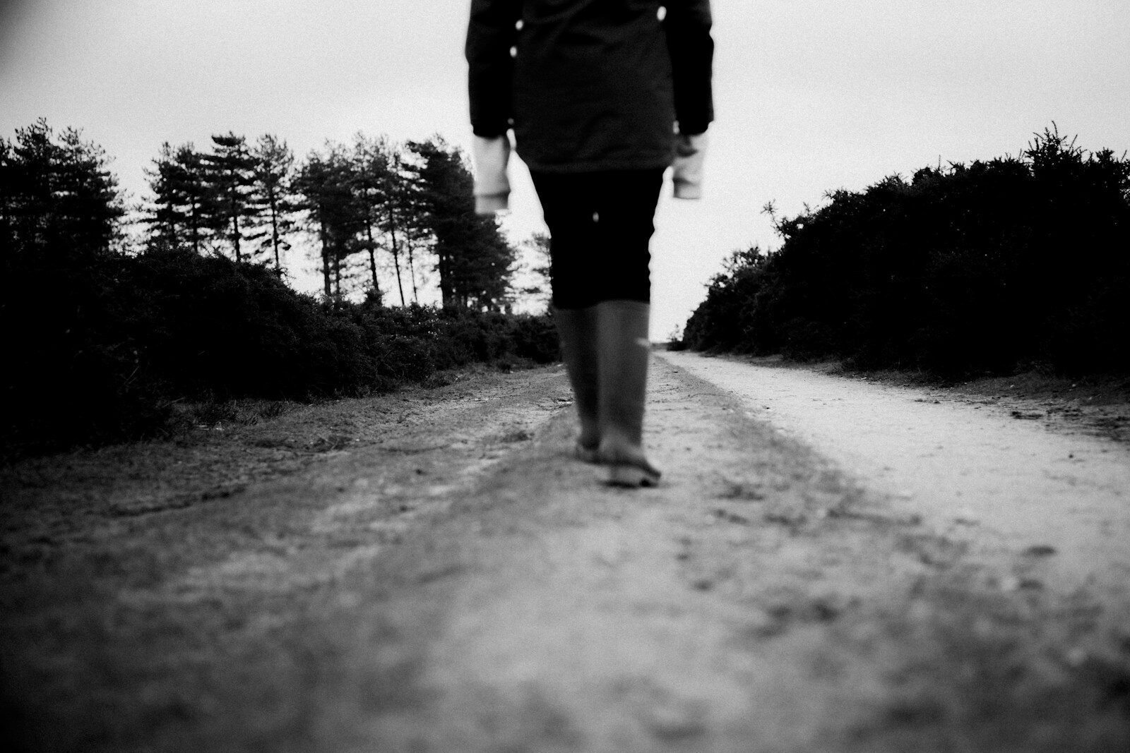 grayscale photo of person walking on road