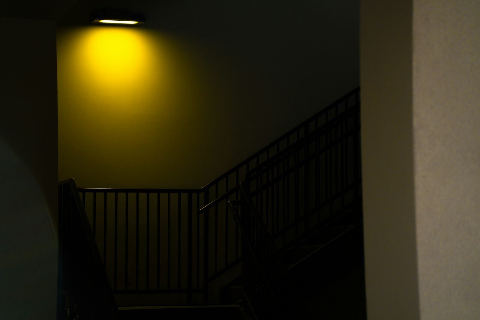 A dark staircase illuminated by a single yellow light.
